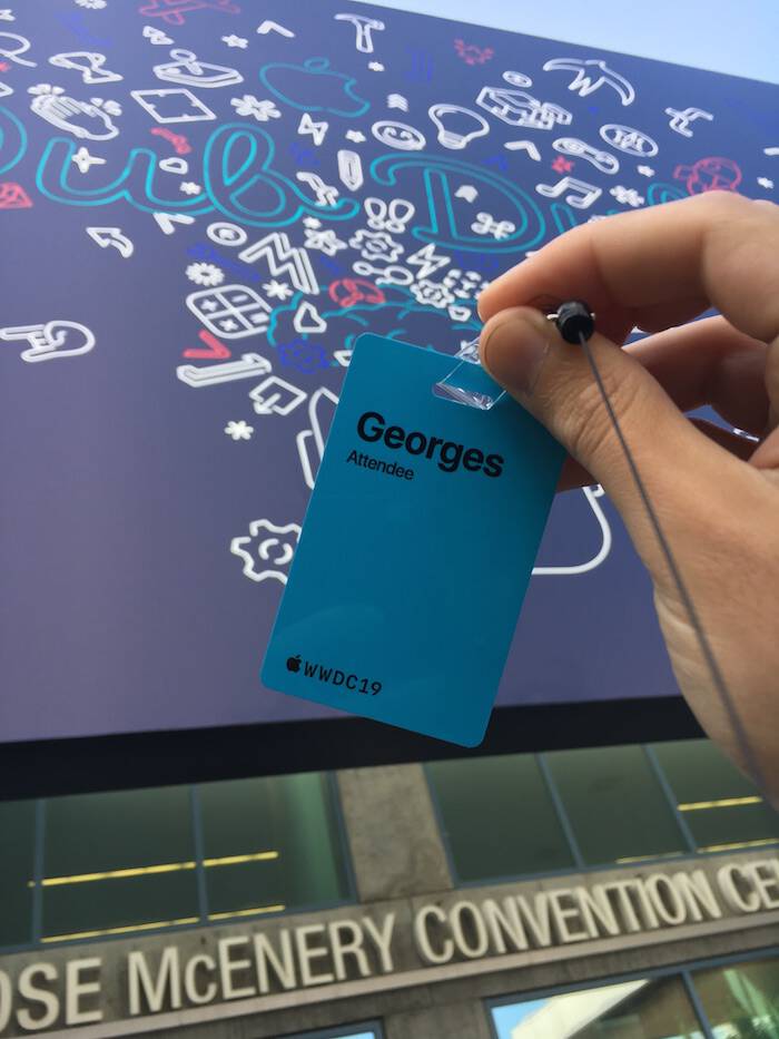 A
                                       photo of the WWDC19 blue badge with name
                                       George followed by the word Attendee and
                                       the logo of WWDC19. The background
                                       contains the graphics of the event
                                       printed on an canvas.  The canvas is on
                                       the front of the San Jose McEnery
                                       Convention Center. The words Ose McEnery
                                       Conevention Ce appear too.